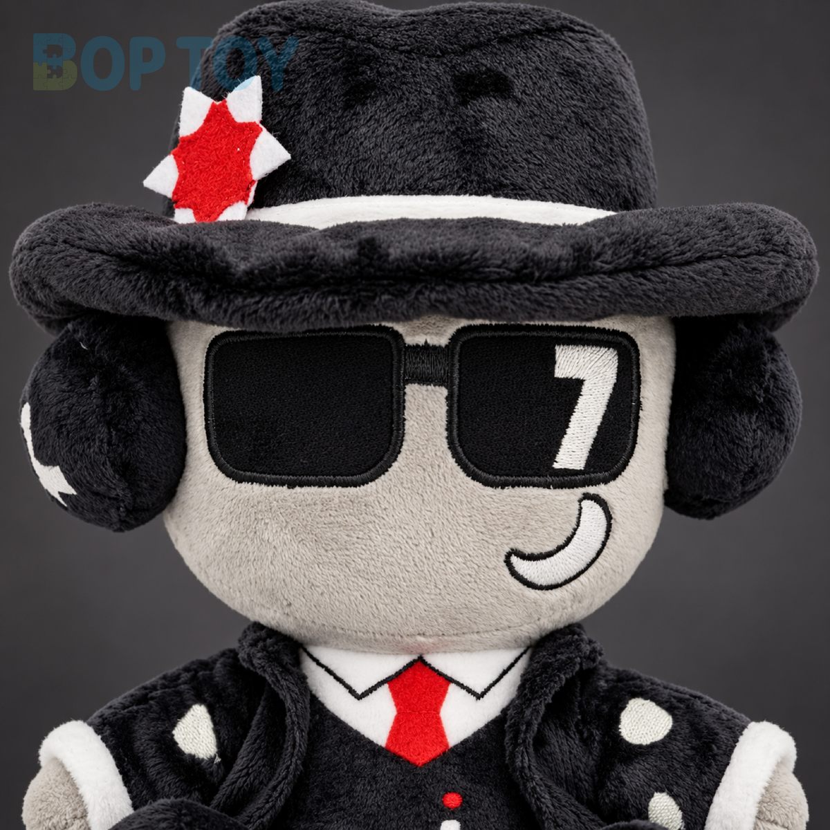 Close-up of fedora badge, embroidered sunglasses and red tie