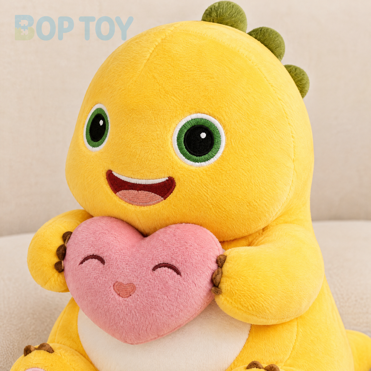 Close-up of the yellow dinosaur plush embroidery and pink heart