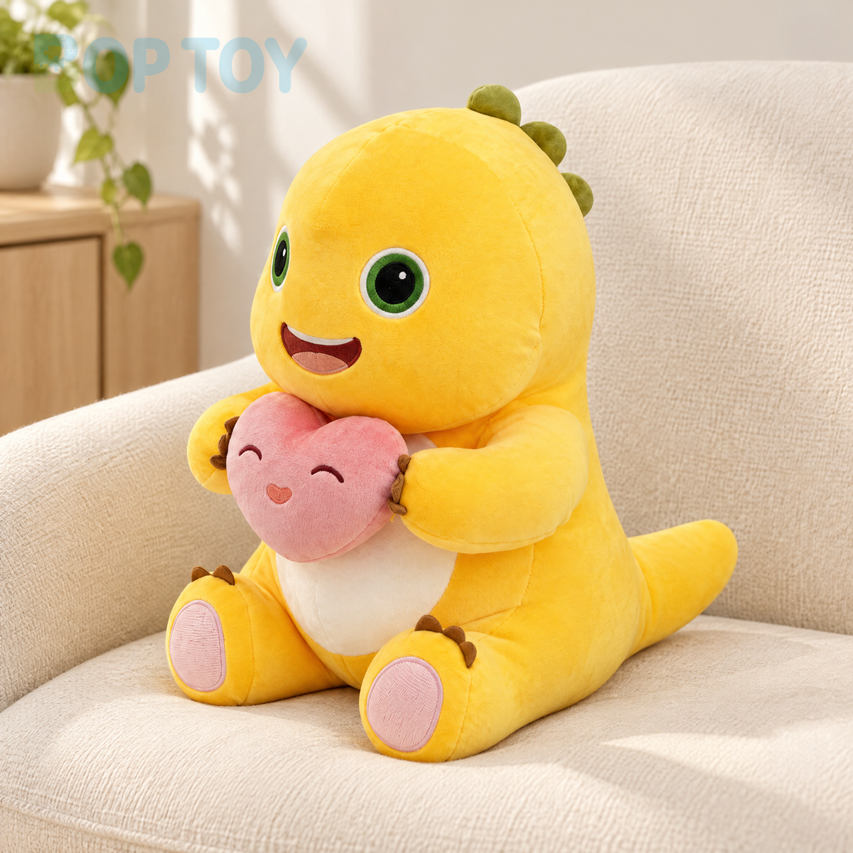 Yellow dinosaur plush holding a pink heart while seated on a cream chair
