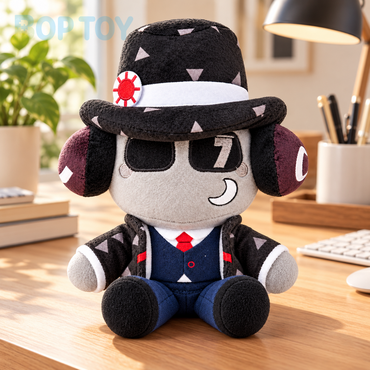 Patterned fedora character plush sitting on a home office desk