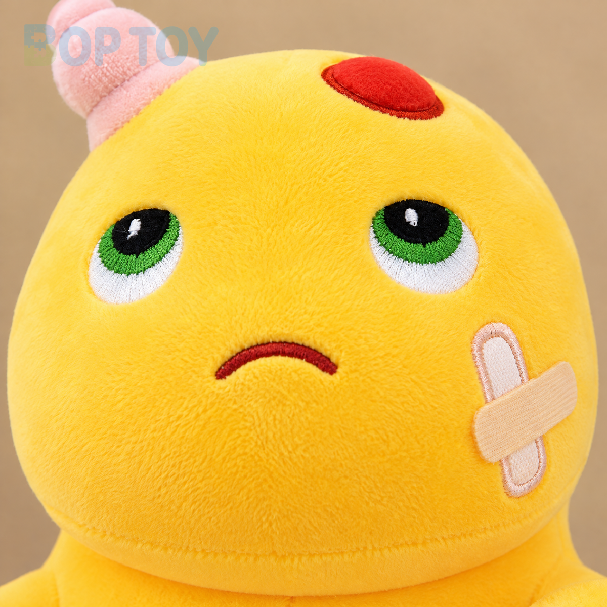 Close-up of embroidered green eyes, forehead patch and crossed cheek bandage