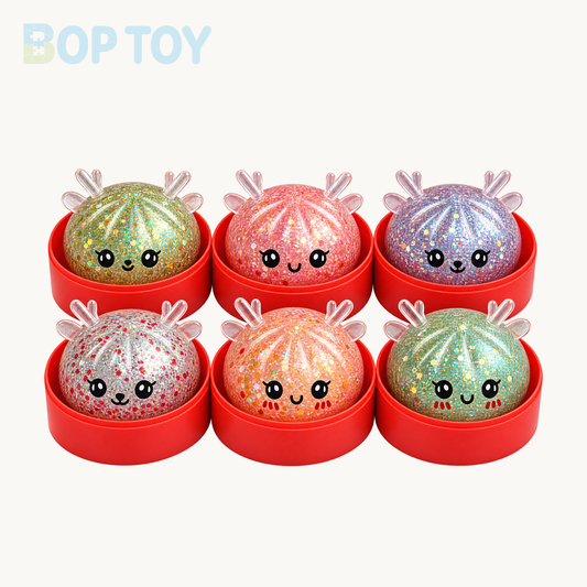 Six Christmas glitter reindeer bun squishy color and face examples with red steamers; single variant contains one randomly selected toy