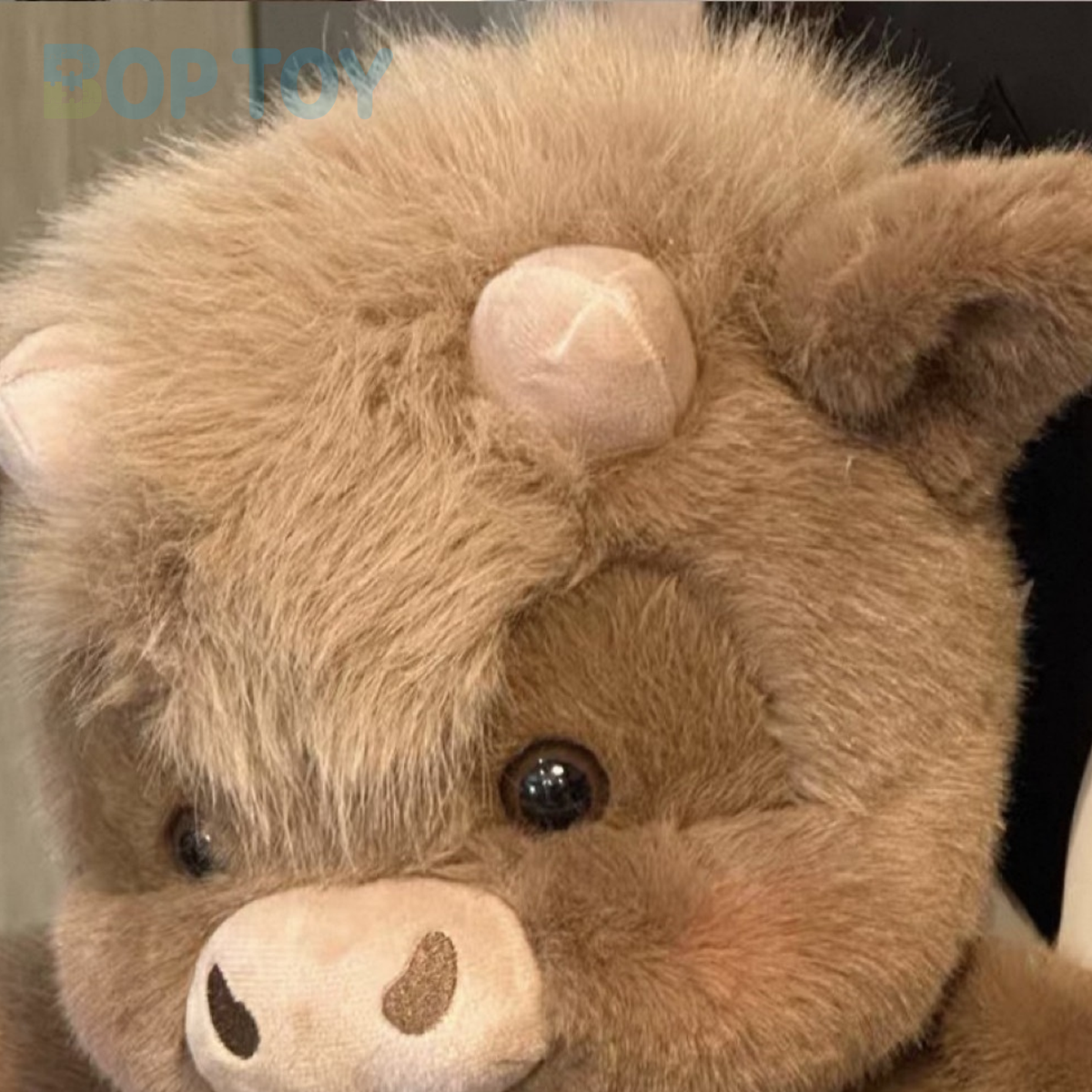 Close-up of the mocha calf plush face, short horns and fluffy fringe